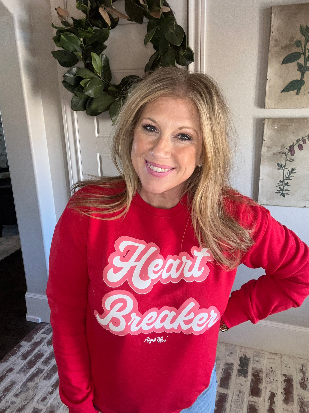 Person wearing a red sweatshirt with 'Heart Breaker' text, standing indoors.