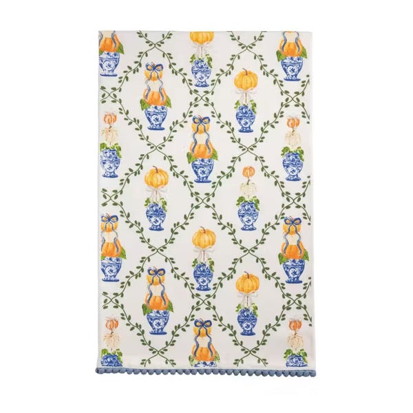 A rectangular white tea towel with a repeating blue and orange chinoiserie pattern of vases, pumpkins, and green vines, finished with a blue scalloped edge.