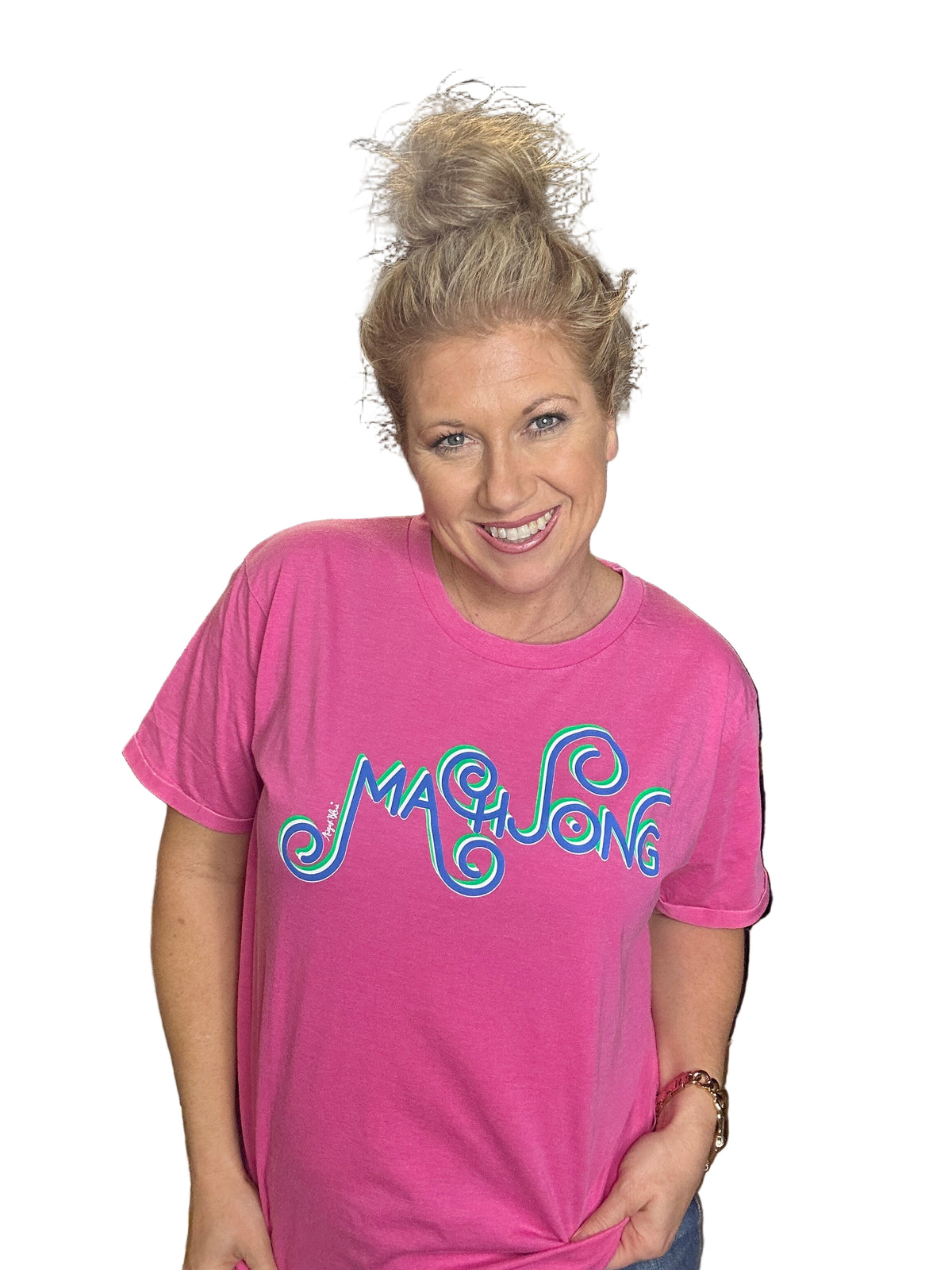 Person wearing a pink t-shirt with colorful text in an indoor setting