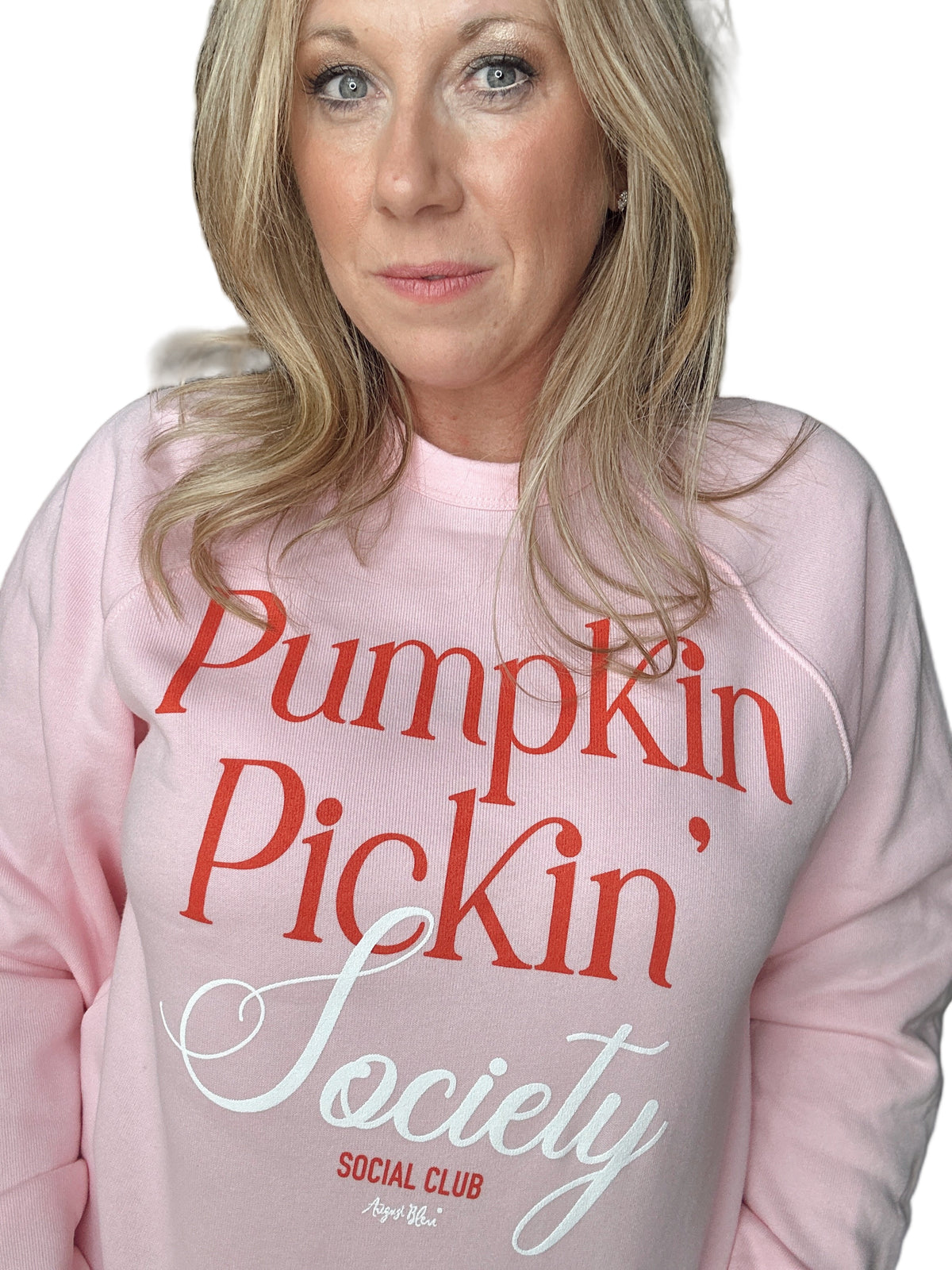 Person wearing a pink sweatshirt with &#39;Pumpkin Pickin&#39; Society Social Club&#39; text.