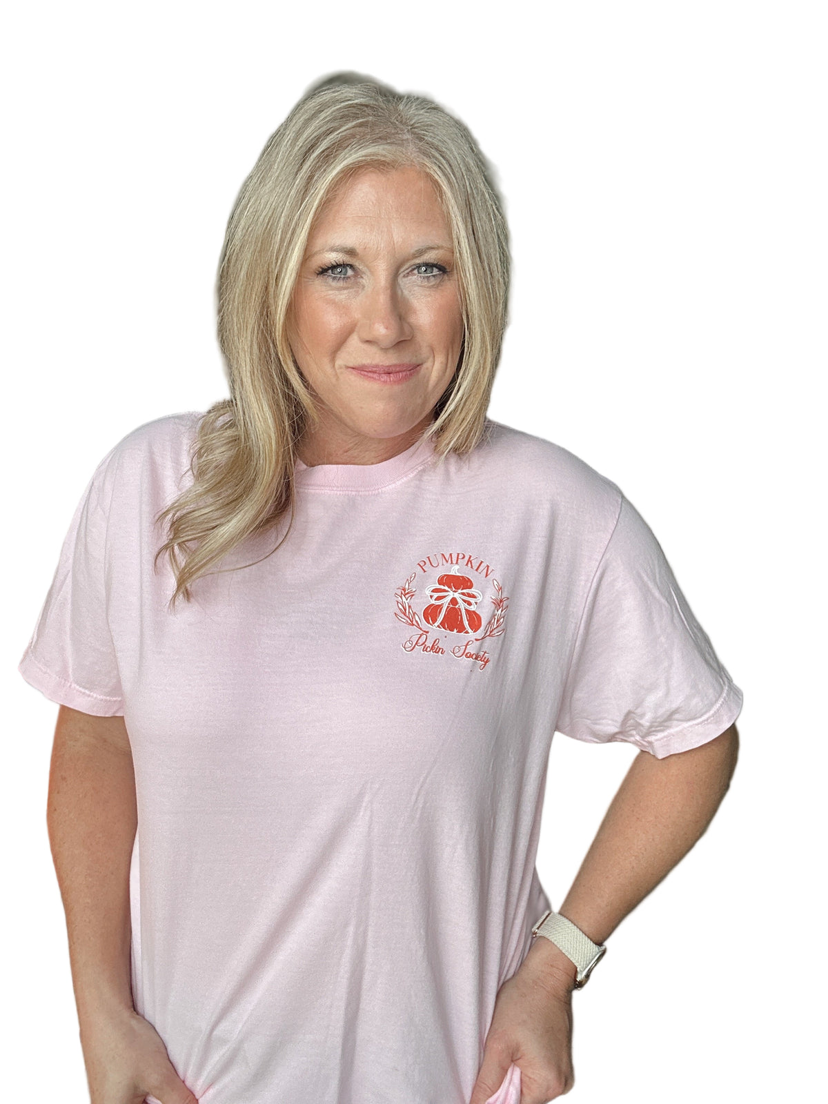 Person wearing a light pink t-shirt with a Pumpkin logo, standing indoors.