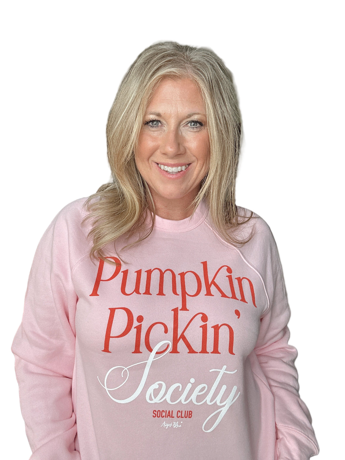 Woman wearing a pink sweatshirt with &#39;Pumpkin Pickin&#39; Society Social Club&#39; text.