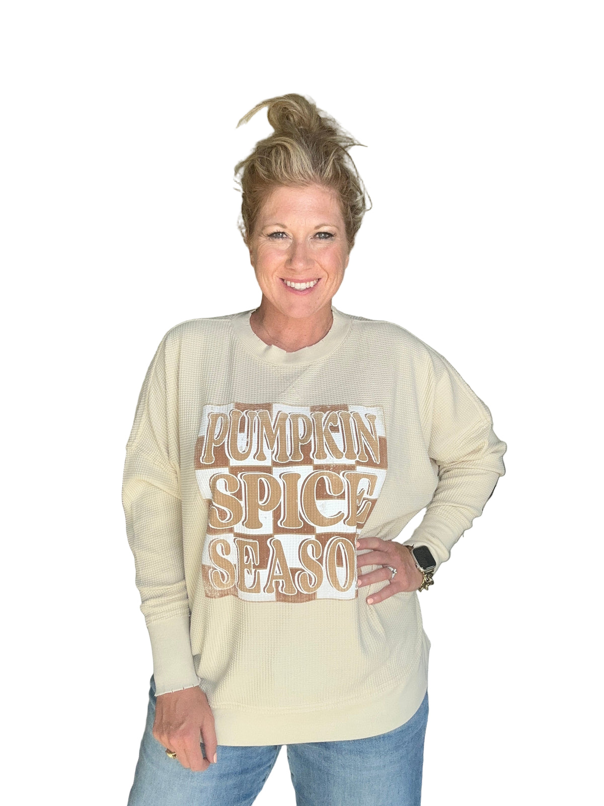 Person wearing a cream-colored sweatshirt with &#39;Pumpkin Spice Latte&#39; text, standing indoors.
