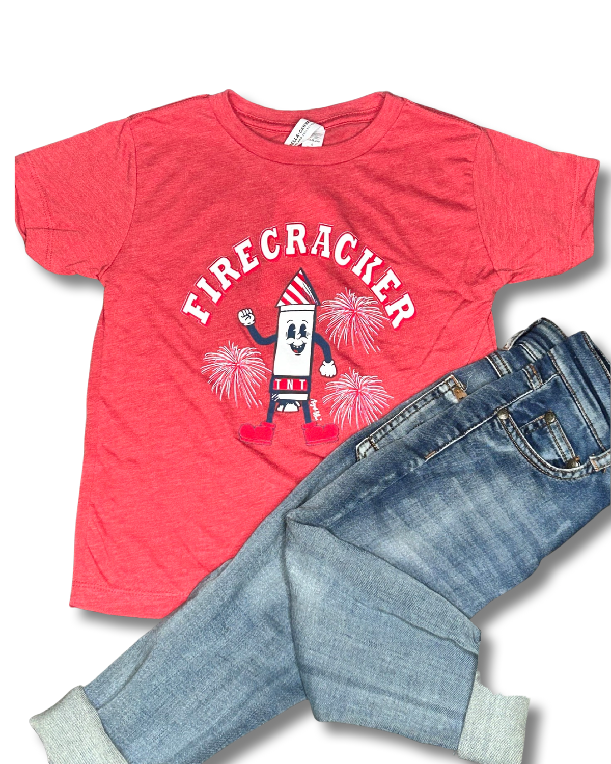Firecracker written in white over a cartoon firecracker and firecracker explosions on a red crew neck kid tee