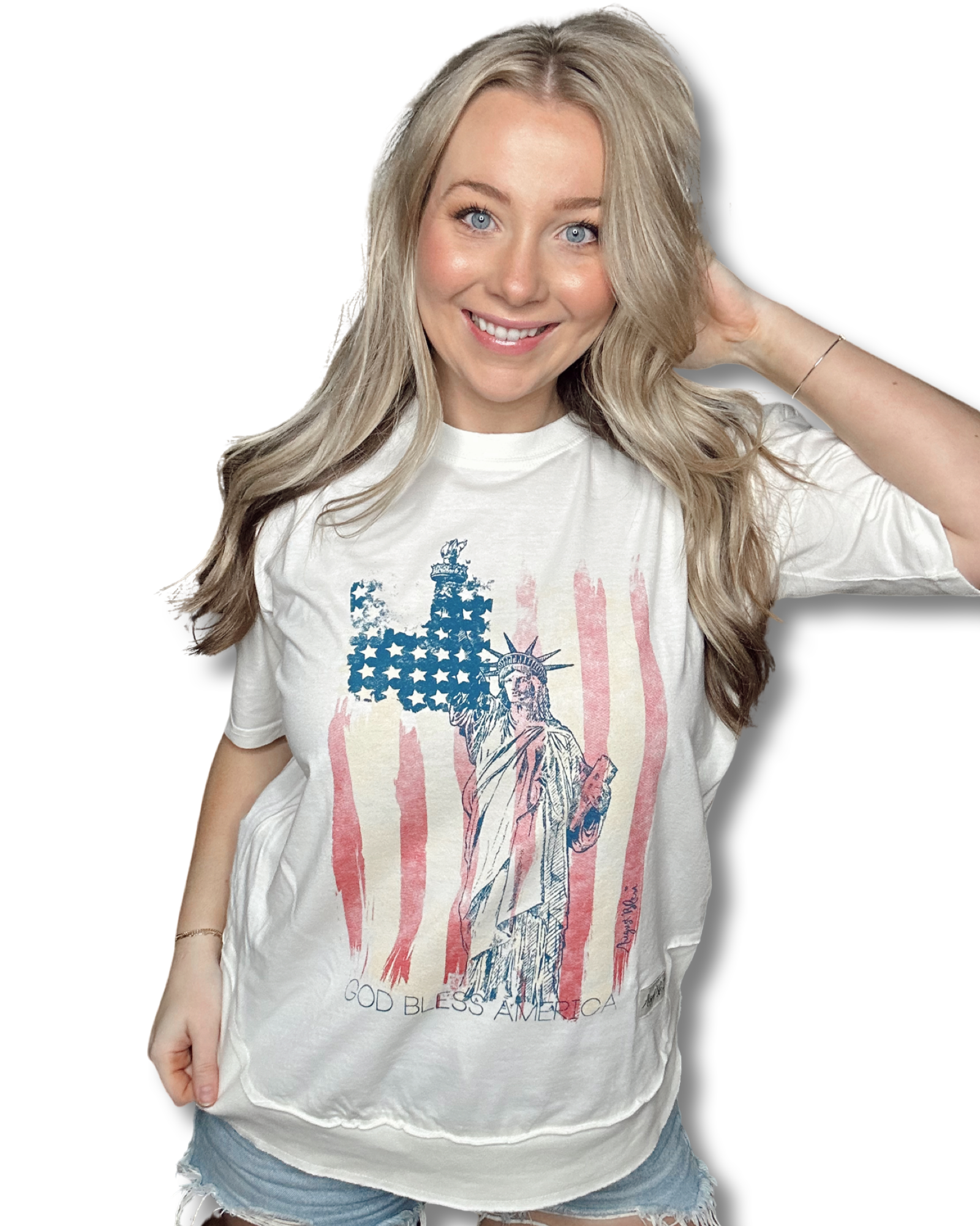 God bless America written underneath a distressed American flag and the statue of liberty on a crew neck belgian cream shirt with a high low hem 